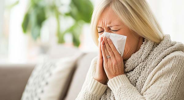 A Woman Sneezing Into a Hankerchief and How you Can Use Natural Remedies to Stop Sneezing.